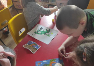 Dzieci składają puzzle z dinozaurami.